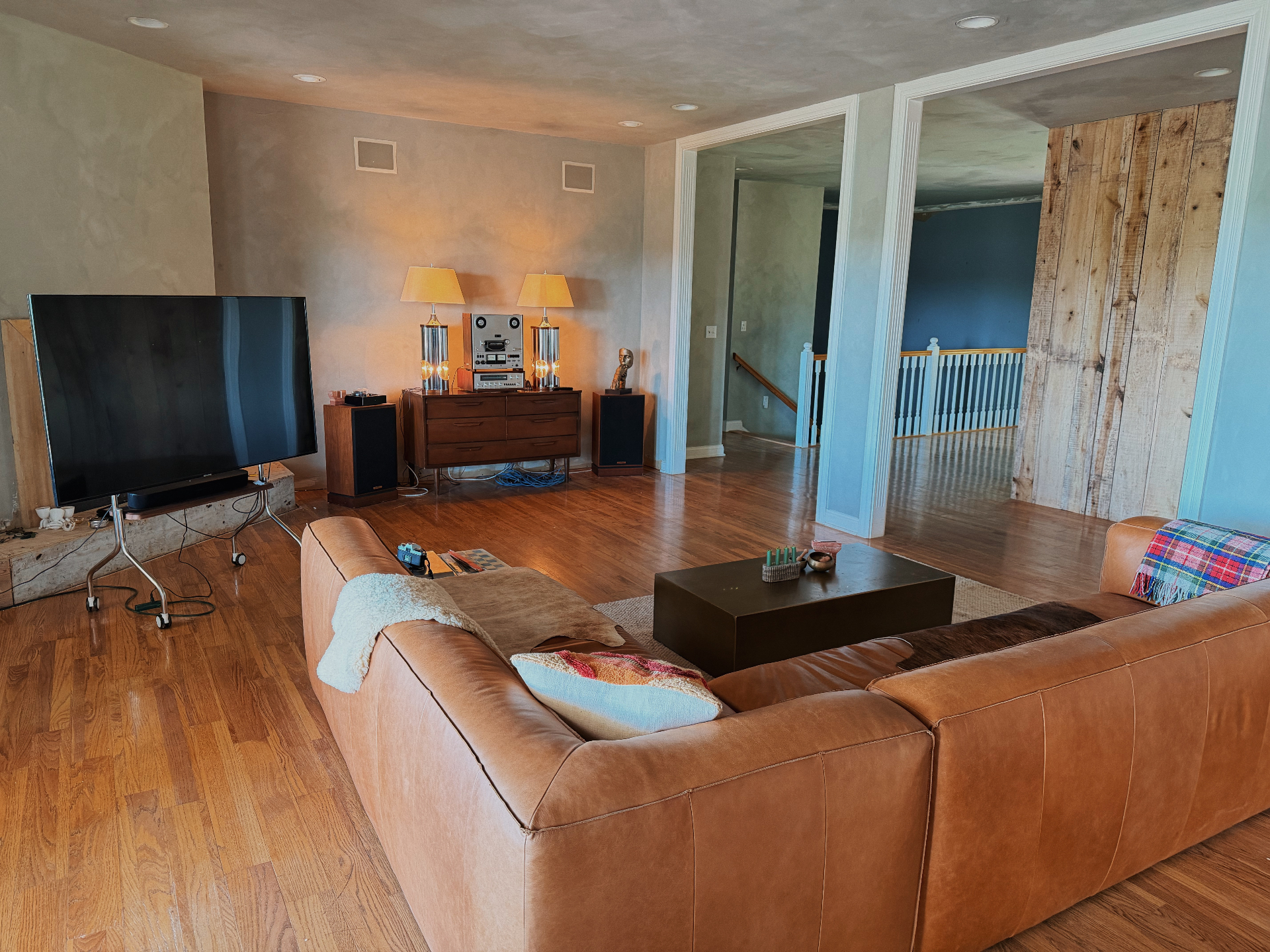 Living room with tan leather sectional, vintage reel-to-reel, and warm lamplight