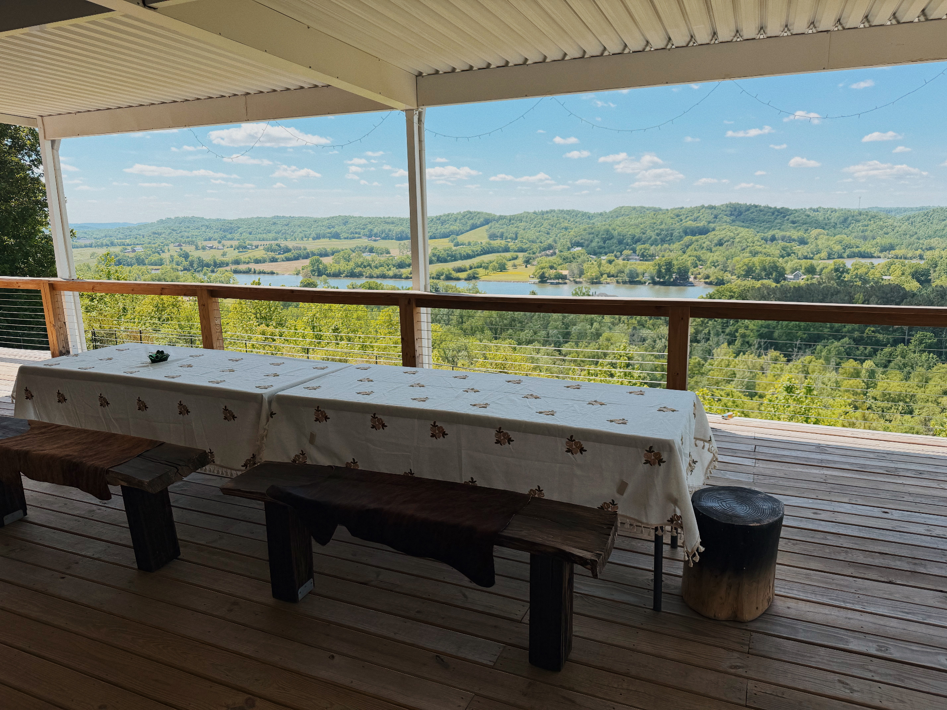 Covered patio with a long farm table looking out to the lake and countryside