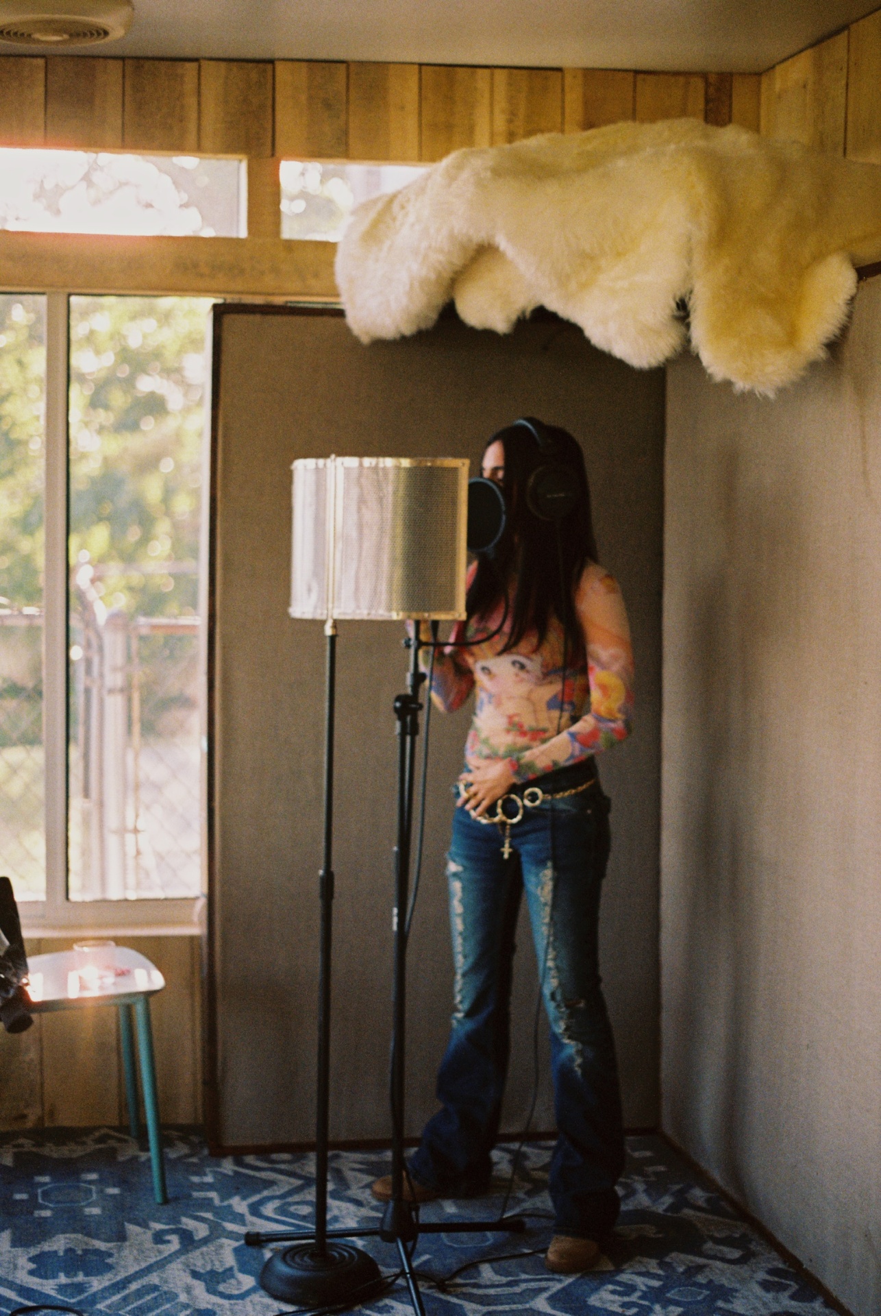 Artist tracking vocals behind the pop filter in the studio booth